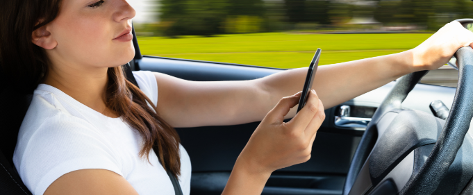 Woman driving while holding her phone